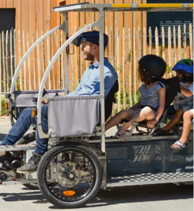 Un adulte et deux enfants circulent à bord d’un Vhélio
