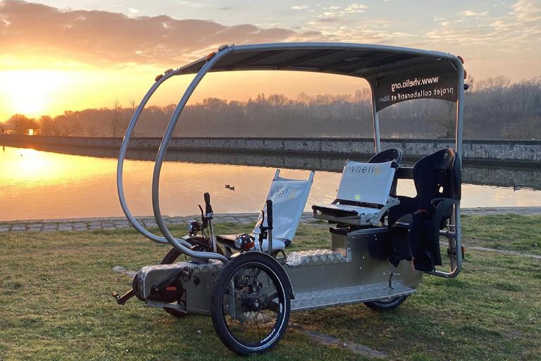 Un Vhélio solaire au bord de l’eau au coucher du soleil